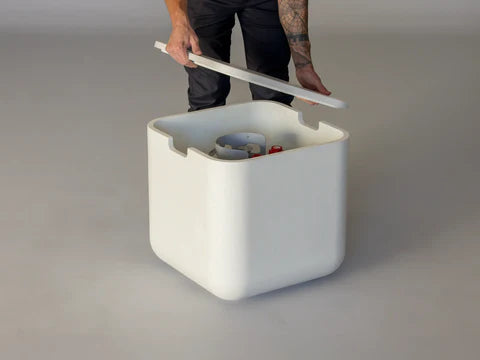 Lumacast - Person lifting a white rectangular container with a tank cover on a gray background