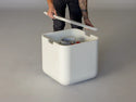 Lumacast - Person lifting a white rectangular container with a tank cover on a gray background