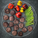 Grill with hamburgers, bell peppers, and asparagus on a dark background
