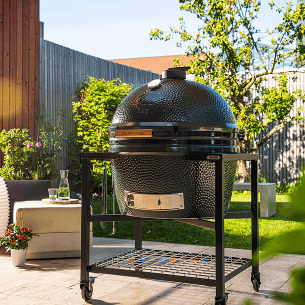 Large ceramic barbecue grill on a stand in an outdoor garden setting
