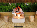 Lumacast Raio soft-Two people sitting by a fire pit on a wooden deck with greenery in the background