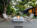 Lumacast Raio soft-Outdoor setting with two chairs and a fire pit on a wooden deck, surrounded by greenery.