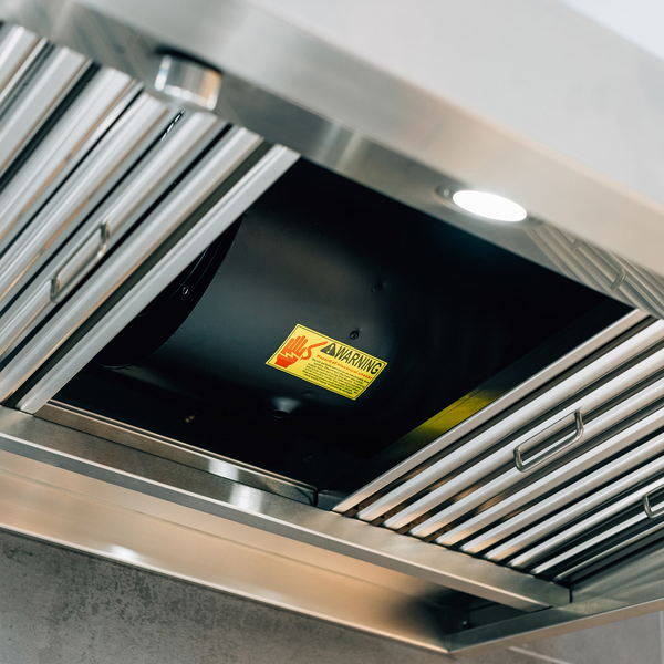 Close-up view of a Summerset stainless steel range hood with a warning label about electrical shock inside.
